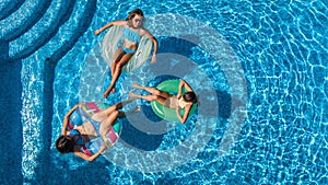 Family in swimming pool aerial drone view from above, happy mother and kids swim on inflatable ring donuts and have fun in water