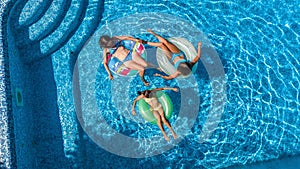 Family in swimming pool aerial drone view from above, happy mother and kids swim on inflatable ring donuts and have fun in water