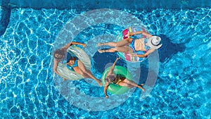 Family in swimming pool aerial drone view from above, happy mother and kids swim on inflatable ring donuts and have fun in water