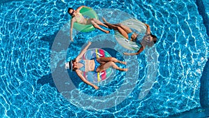 Family in swimming pool aerial drone view from above, happy mother and kids swim on inflatable ring donuts and have fun in water