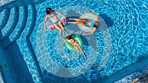 Family in swimming pool aerial drone view from above, happy mother and kids swim on inflatable ring donuts and have fun in water