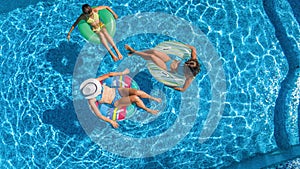 Family in swimming pool aerial drone view from above, happy mother and kids swim on inflatable ring donuts and have fun in water