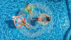 Family in swimming pool aerial drone view from above, happy mother and kids swim on inflatable ring donuts and have fun in water