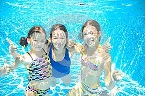 Family swims in pool under water, happy active mother and children have fun, fitness and sport