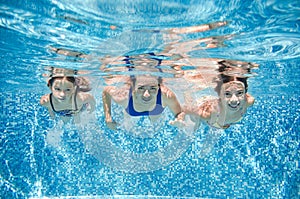 Family swims in pool under water, happy active mother and children have fun, fitness and sport with kids on summer vacation