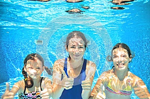 Family swims in pool under water, happy active mother and children have fun, fitness and sport