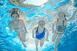 Family swims in pool under water, happy active mother and children have fun, fitness and sport with kids on vacation