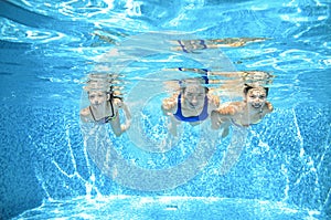Family swims in pool under water, happy active mother and children have fun, fitness and sport with kids on vacation