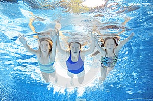 Family swims in pool under water, happy active mother and children have fun, fitness and sport with kids on vacation