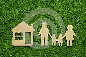 Family symbols and houses made of natural wood on the background of green grass symbolize the eco-house.