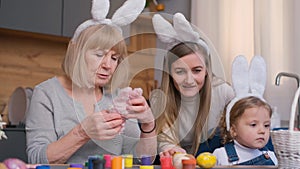 Family at table, sharing smiles, decorating Easter eggs. Fun event in the house