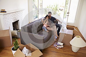 Family Take A Break On Sofa Using Laptop On Moving Day