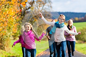 Family take walk in autumn forest flying kite