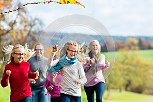 Family take walk in autumn forest flying kite