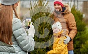 Family taking picture of christmas tree at market