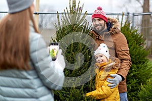 Family taking picture of christmas tree at market