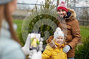 Family taking picture of christmas tree at market