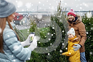 Family taking picture of christmas tree at market