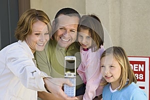 Family Taking Self-Portrait In Front Of New House