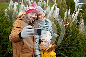 Family taking selfie with christmas tree at market