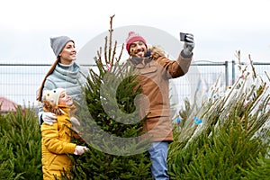 Family taking selfie with christmas tree at market