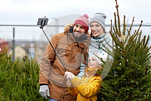 Family taking selfie with christmas tree at market