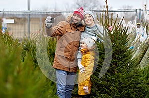 Family taking selfie with christmas tree at market