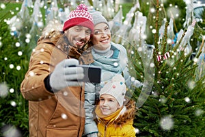 Family taking selfie with christmas tree at market