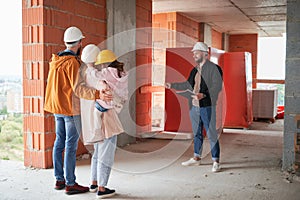 Family talking with builder at construction site.