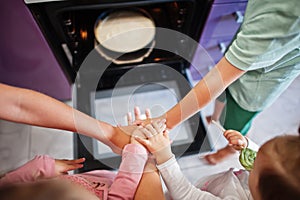 We are family team! Hands in hands. Mother with kids cooking at kitchen, happy children`s moments. Cheesecake in the oven