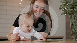 Family, technology and motherhood concept - happy smiling young mother with little baby and tablet pc computer at home