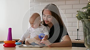 Family, technology and motherhood concept - happy smiling young mother with little baby and tablet pc computer at home