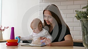 Family, technology and motherhood concept - happy smiling young mother with little baby and tablet pc computer at home