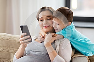 Pregnant mother and son with smartphone at home