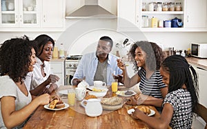 Family With Teenage Children Eating Breakfast In Kitchen