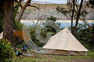 Family tent setup at the campsite surrounding by bush forest near the ocean bay in Australia. Family vacation travel camping