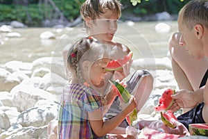 Family of three beach picnic with watermelon