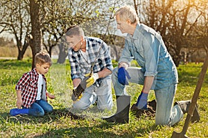 Family of three generations planting the tree in the garden