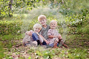 Family of Three Happy Young Children Posing Outside in Forest