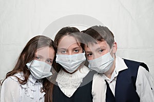 family of three little kids in medical masks and school uniform during coronavirus COVID-19 epidemy quarantine with copy