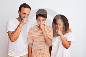Family of three, mother, father and son standing over white isolated background feeling unwell and coughing as symptom for cold or