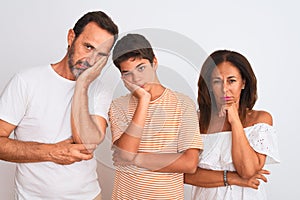 Family of three, mother, father and son standing over white isolated background thinking looking tired and bored with depression