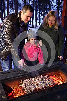 Family of three people doing barbecues on a winter