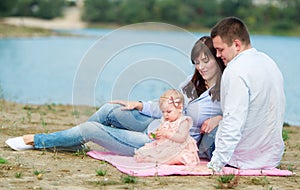 The family of three people has a rest outdoors