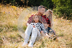 Family of three people rest in the mountains. They sat down to rest, drink water after a hard climb to the mountain