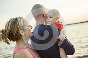 Family of three person is standing on sunset and sea backdrop