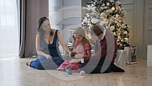 Family of Three Petting Kitten by Christmas Tree