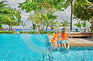 Family of three by poolside. Resort swimming pool at Seychelles