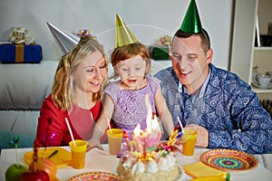 Family of three sits at birthday table, daughter