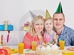 Family of three sits cheek to cheek at birthday photo